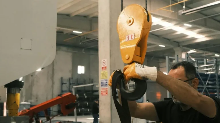 Worker preparing lifting hook for equipment testing in an industrial workshop – Proof Load Test vs Load Test